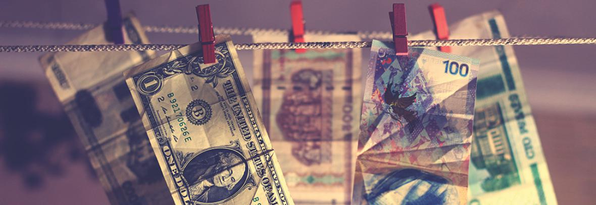 Image of US dollar bill and foreign dollars hanging on close line