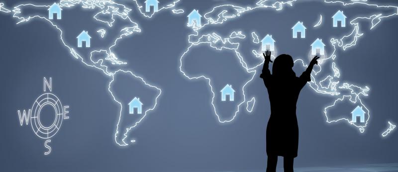 woman standing in front of digital world map with house logos