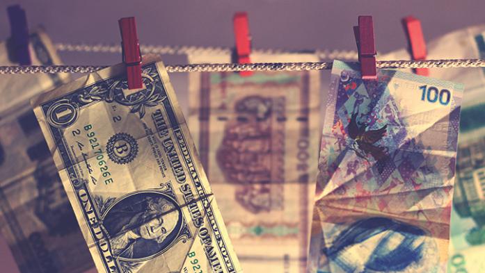Image of US dollar bill and foreign dollars hanging on close line