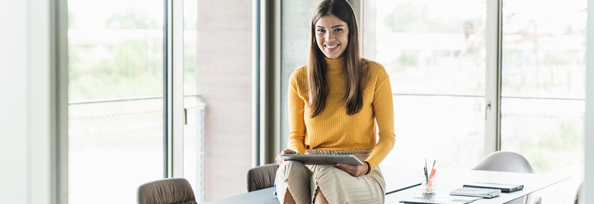 Photo of Millennial Realtor sitting on a desk using a tablet computer