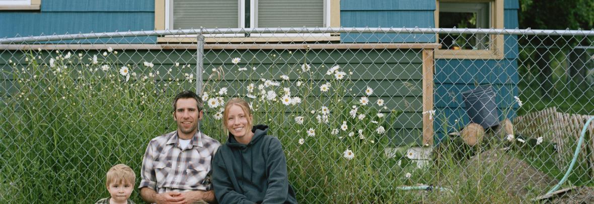 couple and child sitting in front of a chain link fence 