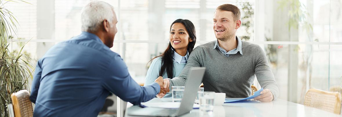 Real Estate agent shaking hands with young sellers couple