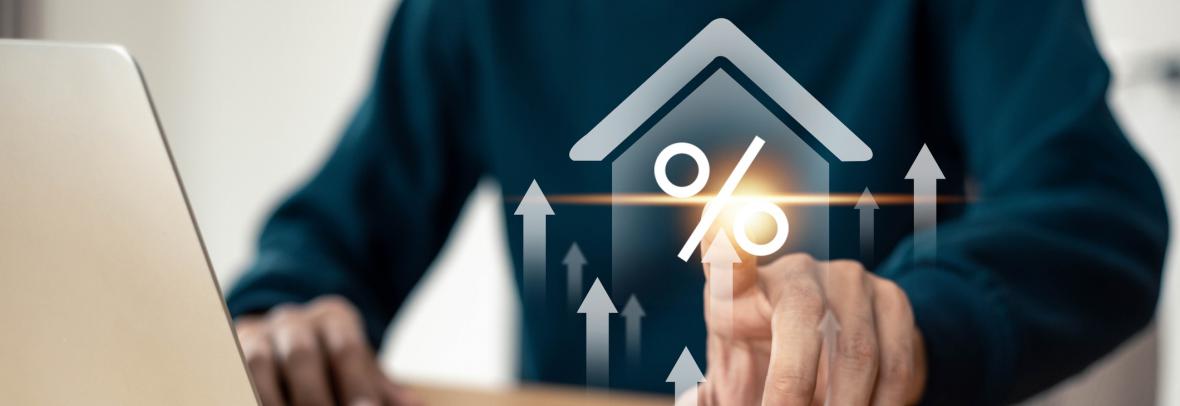 Man at laptop with finger touching an illustration of a percentage sign with a house