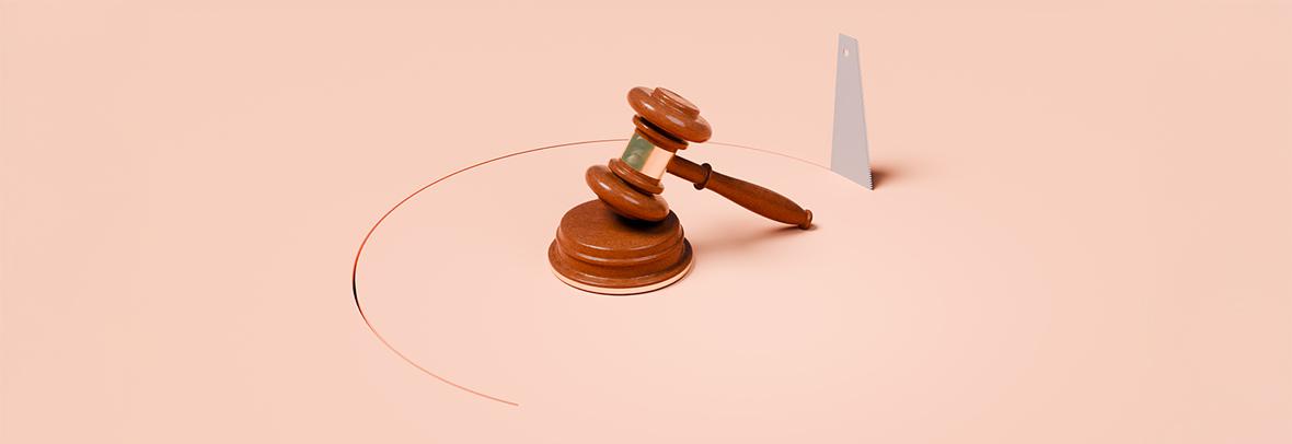 wooden gavel on pink background with a saw cutting a circle