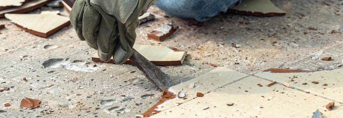 cropped hand of worker removing tile from floor
