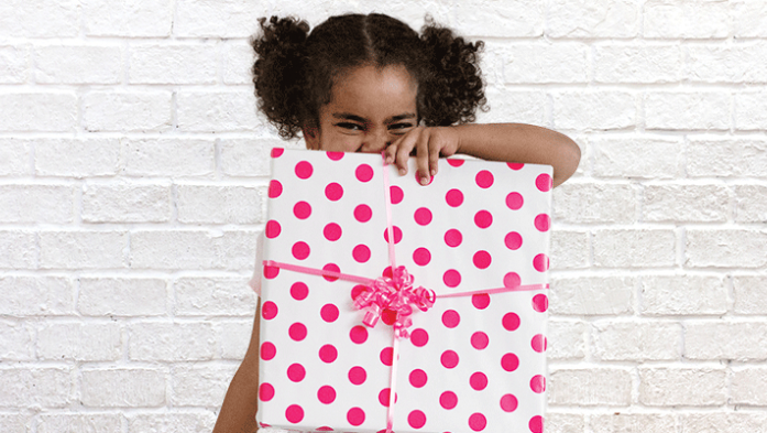 Photo of little girl holding a present wrapped in pink polka dotted wrapping paper