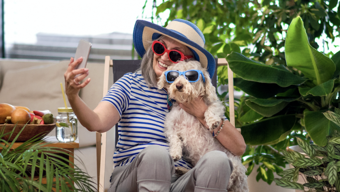 Woman and her dog wear sunglasses while taking a phone selfie