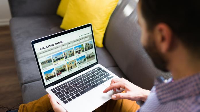 Man looking at real estate listings on a laptop