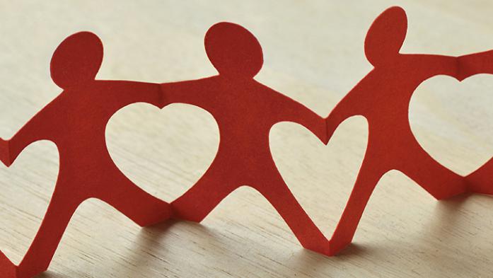 paper cut outs of people holding hands creating heart shapes in between