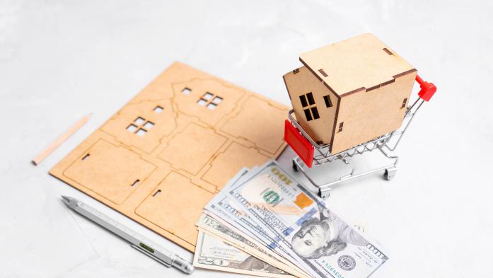 A cut-out, put-together toy home with money laying on top