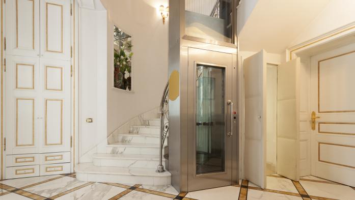 Small elevator beside the staircase of an upscale home