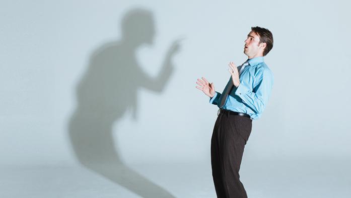 Photo of a man being criticized by a shadow of himself