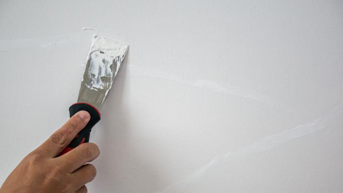 Plasterer hand repair crack white wall