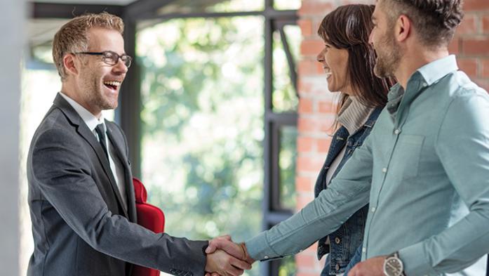 Real Estate agent shaking hands with a couple