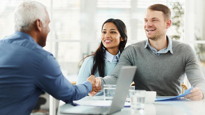 Real Estate agent shaking hands with young sellers couple