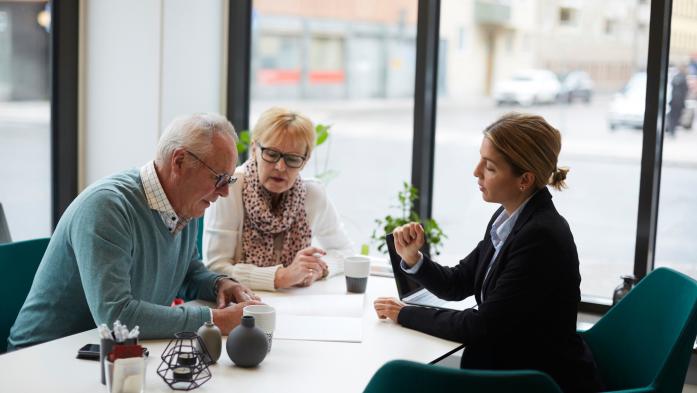 Realtor at desk going over paperwork with an older couple