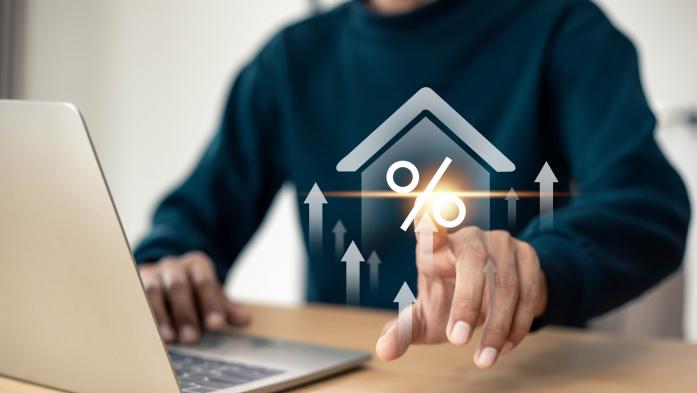 Man at laptop with finger touching an illustration of a percentage sign with a house