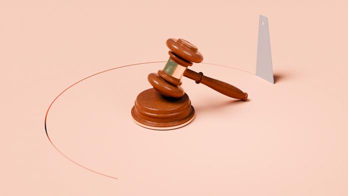 wooden gavel on pink background with a saw cutting a circle