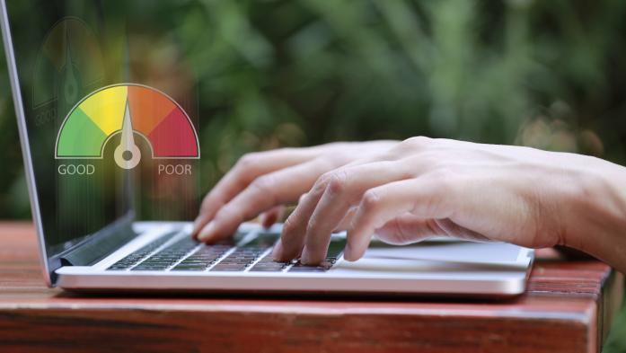 hands typing on laptop with credit score meter