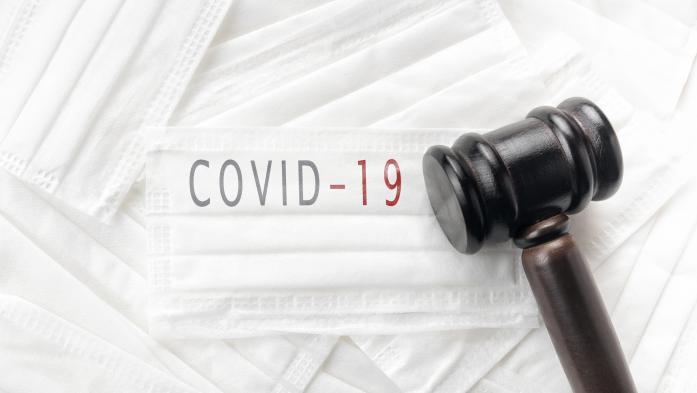 judge's gavel on top of masks that say COVID-19