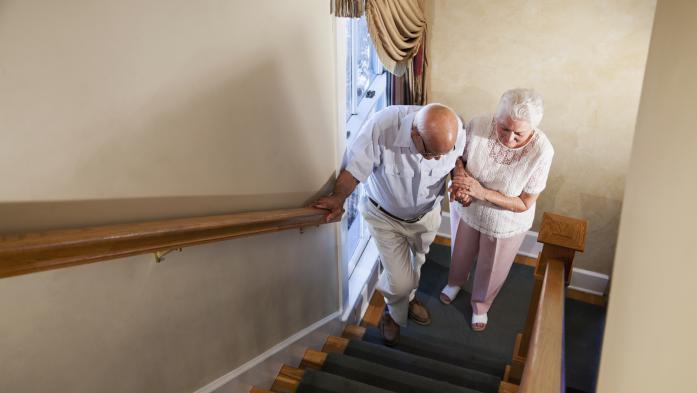 Older woman helps older man climb the stairs