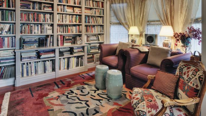 cozy living room with 3 armchairs and full bookcase wall