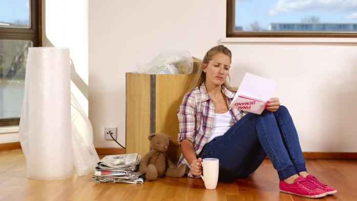 Unhappy female renter sits on the floor with a demand letter in her hand