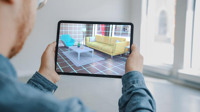 Photo of a man looking at a virtual rendering of a living room on his tablet